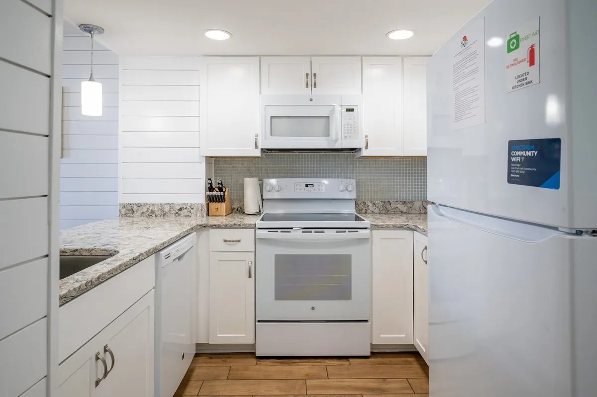 This image captures the heart of the kitchen space, highlighting the gleaming granite countertop, crisp white cabinetry, and full suite of stainless steel appliances. The layout is open and inviting, suggesting plenty of space for preparing family meals or entertaining guests.