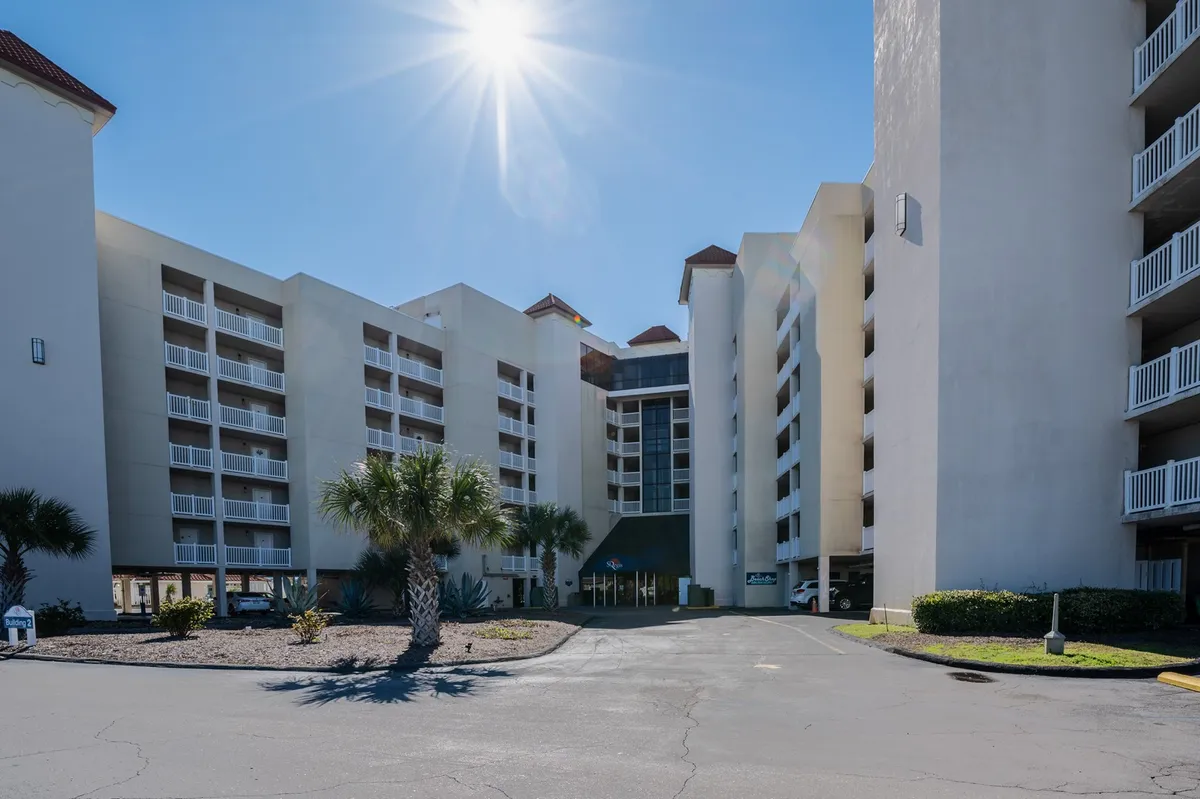 This exterior shot captures the central entrance of the resort, framed by tall palm trees and bathed in bright sunlight. The inviting glass doors signal the start of a fun-filled stay, while the landscaped area adds to the welcoming atmosphere.