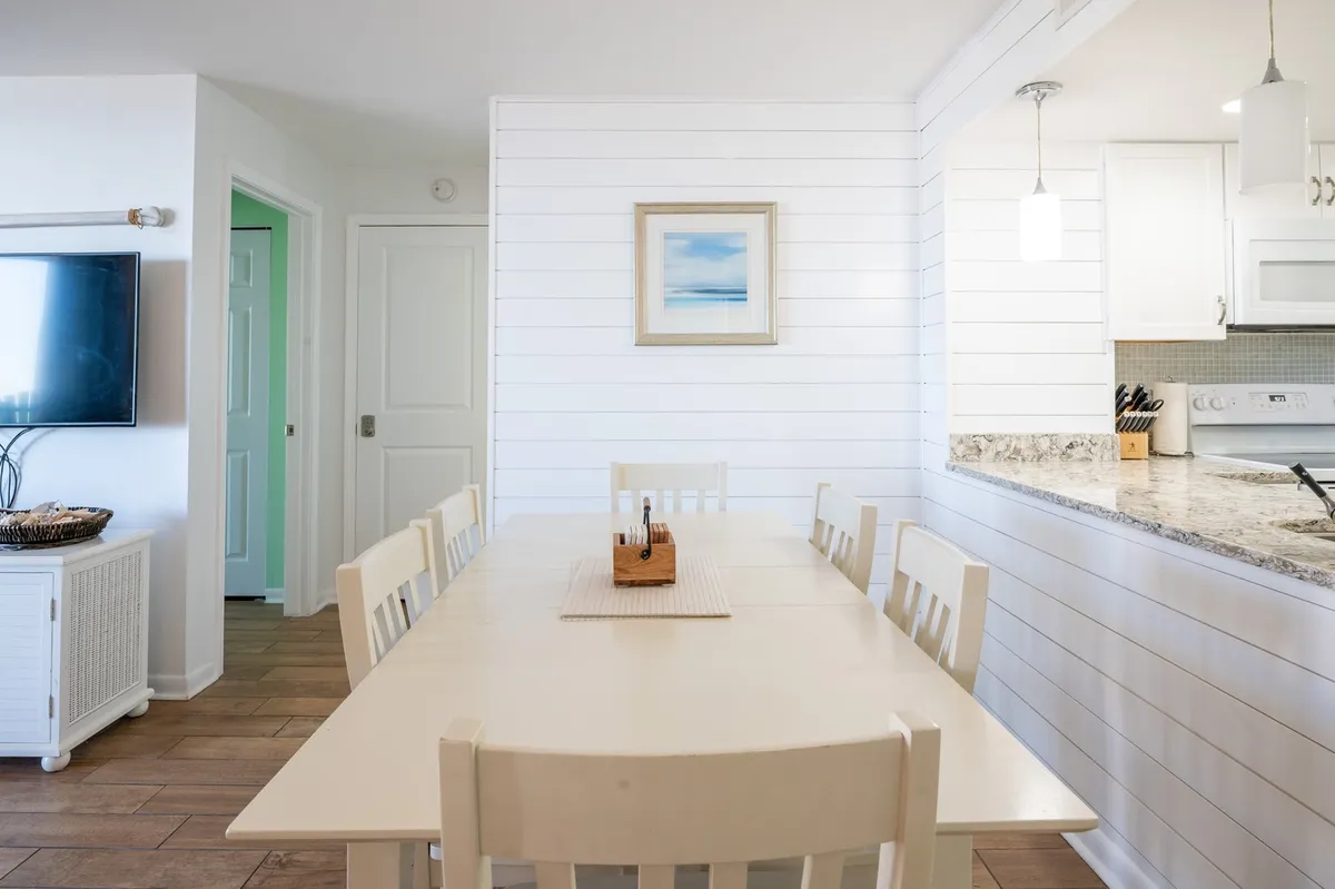 A bright, welcoming dining and kitchen area with a spacious table set for family meals, warm wall art, and an inviting kitchen. The atmosphere is relaxed, perfect for gathering and planning out seasonal activities or enjoying time together between adventures.