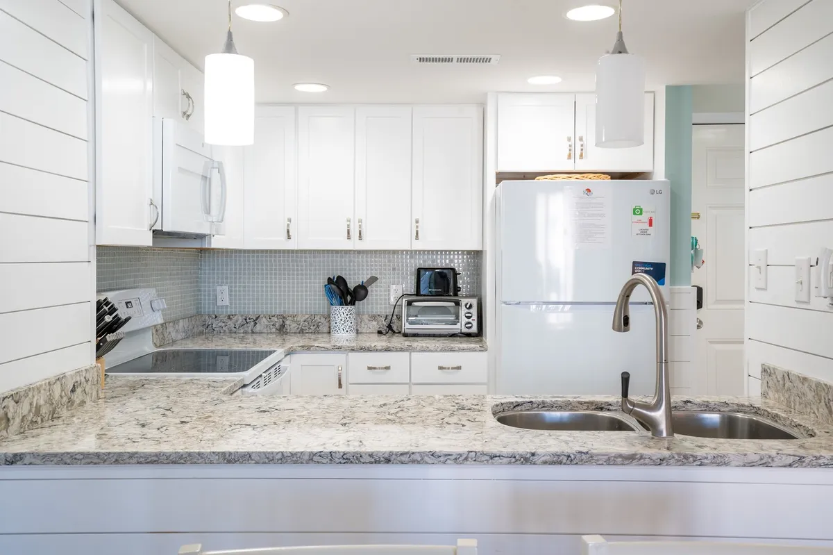 A second angle on the kitchen, showing the granite countertops, white cabinetry, and visible appliances. The space feels functional and homey, ideal for preparing everything from everyday snacks to special dinners.