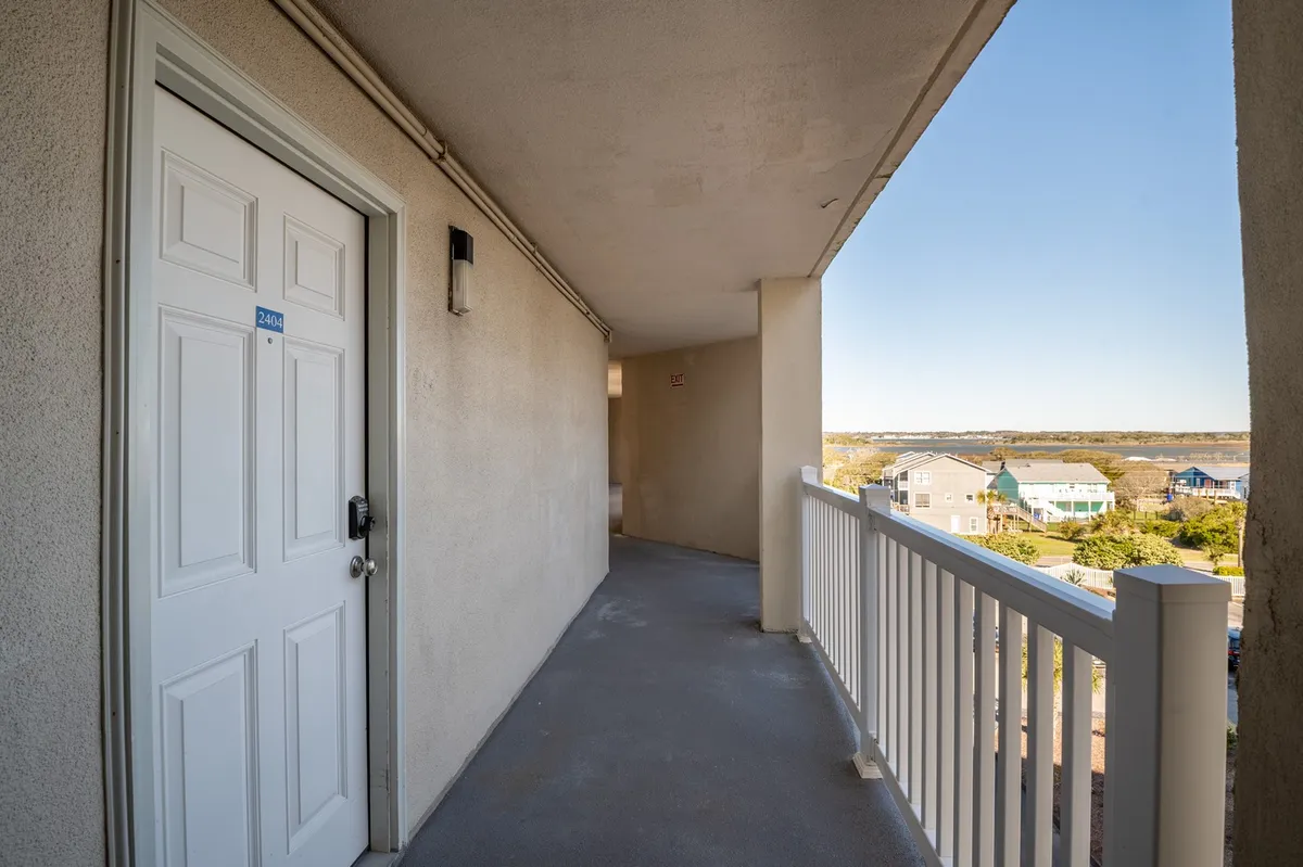A calm exterior scene featuring a balcony railing and a view overlooking neighboring houses and community spaces. The tranquil setting is ideal for watching sunsets, enjoying relaxing moments, or observing resort activities from above.